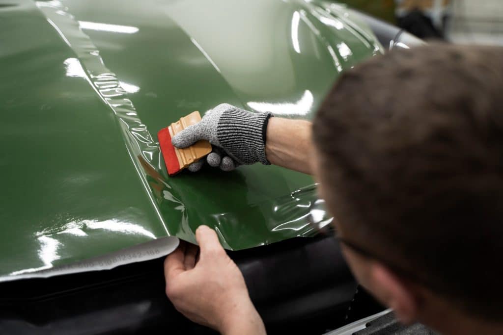 Personne entrain de mettre un film coloré sur une voiture